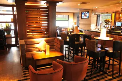 a restaurant with tables and chairs and a bar at Mondo Hotel in Coatbridge