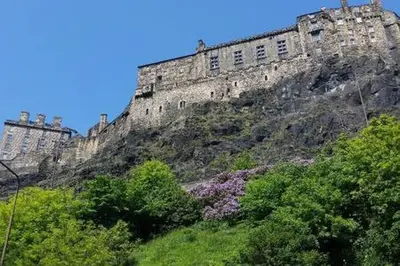 a castle on top of a hill with trees at The Wee Highland Coo in Edinburgh
