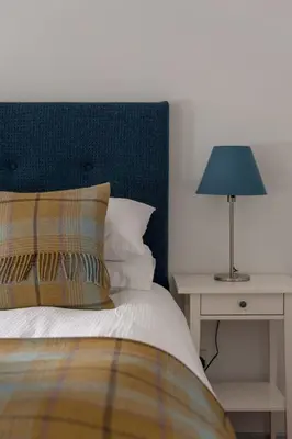 a bed with a blue headboard and a table with a lamp at The Wee Highland Coo in Edinburgh