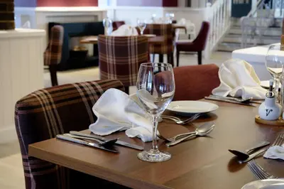 a wooden table with a wine glass on top of it at The Crown Hotel in Newton Stewart