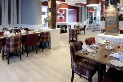 a dining room with tables and chairs in a restaurant at The Crown Hotel in Newton Stewart