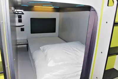 a small room with a white bed and a tv at Kick Ass Grassmarket (18+) in Edinburgh