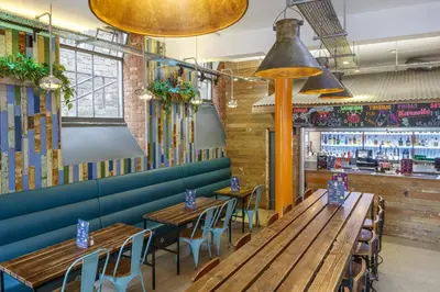 a restaurant with wooden tables and chairs and a bar at Kick Ass Grassmarket (18+) in Edinburgh
