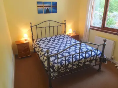 a bed in a bedroom with two lamps and a window at Trefoil Holiday Home in Strachur
