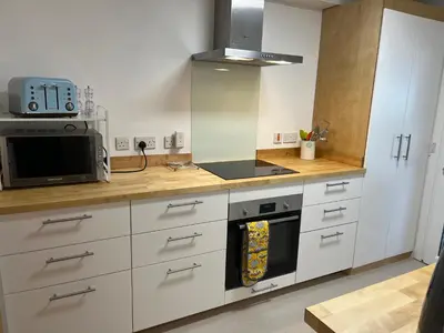 a kitchen with white cabinets and a stove top oven at Pottery Cottage, Lochans Lodge in Stranraer