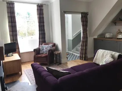 a living room with a purple couch and a chair at The Cottage in Dunblane