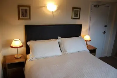 a bedroom with a large bed with two lamps on tables at Highland House Callander in Callander