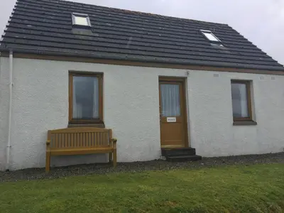 a house with a bench in front of it at Shieling Holidays Mull in Craignure