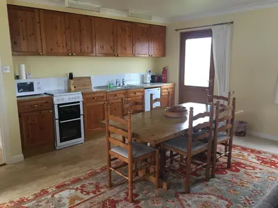 a kitchen with a wooden table and wooden cabinets at Shieling Holidays Mull in Craignure