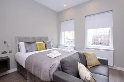 a bedroom with a large bed and a couch at Nelson Mandela Place Apartments in Glasgow