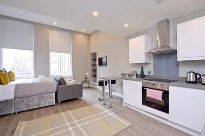 a kitchen and living room with a bed in a room at Nelson Mandela Place Apartments in Glasgow