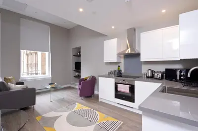 a kitchen with white cabinets and a living room at Nelson Mandela Place Apartments in Glasgow