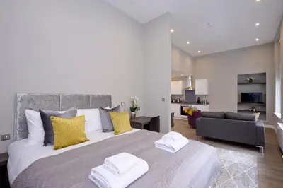 a bedroom with a large bed with yellow pillows at Nelson Mandela Place Apartments in Glasgow