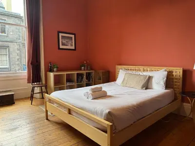 a bedroom with a large bed with orange walls at Classic Edinburgh Flat in the heart of Morningside in Edinburgh