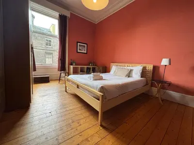a bedroom with a bed and a red wall at Classic Edinburgh Flat in the heart of Morningside in Edinburgh