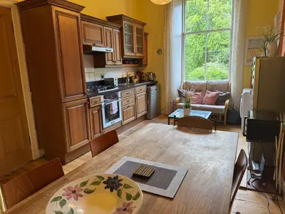 a kitchen with wooden cabinets and a table in a room at Classic Edinburgh Flat in the heart of Morningside in Edinburgh