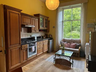 a kitchen with wooden cabinets and a couch and a table at Classic Edinburgh Flat in the heart of Morningside in Edinburgh