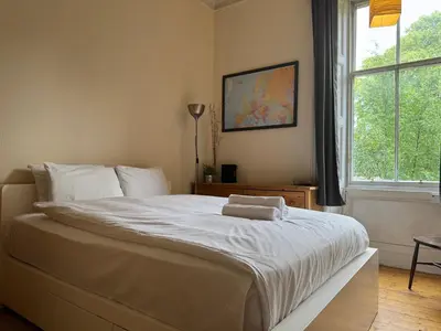 a bedroom with a large white bed with a window at Classic Edinburgh Flat in the heart of Morningside in Edinburgh