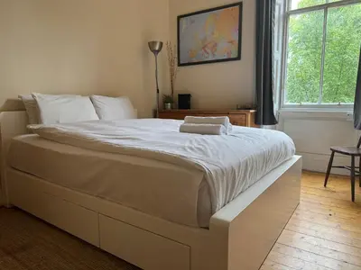 a large white bed in a bedroom with a window at Classic Edinburgh Flat in the heart of Morningside in Edinburgh