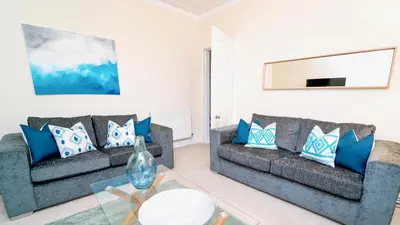 a living room with two couches and a glass table at Snug - Tùr Sealladh Apartment in Helensburgh