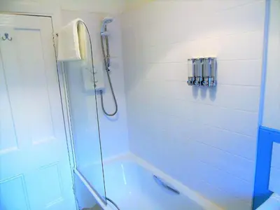 a white bathroom with a shower and a tub at Snug - Tùr Sealladh Apartment in Helensburgh