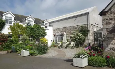 a house with a patio and flowers in front of it at River View Knockraich Farm in Fintry