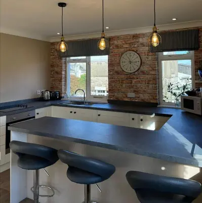 a kitchen with a large counter with two bar stools at River View Knockraich Farm in Fintry