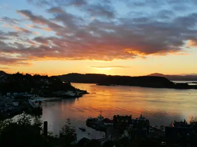a sunset over a body of water with a city at Gramarvin B&B in Oban