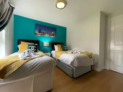 two beds in a room with a blue wall at HLA - KING COURT APARTMENT 2 in Motherwell