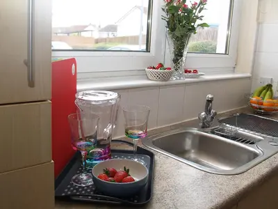 a tray with two glasses and a bowl of strawberries next to a sink at HLA - KING COURT APARTMENT 2 in Motherwell