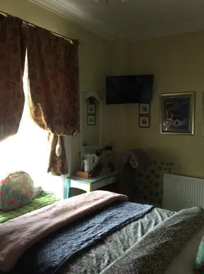 a bedroom with a bed and a window with a television at Lagganbeg Guest House in Oban