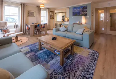 a living room with blue couches and a coffee table at Marina View Apartment in Inverkip