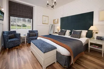 a bedroom with a large bed and two chairs at Cringletie House in Peebles