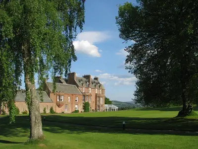 a large brick house with trees in the foreground at Cringletie House in Peebles