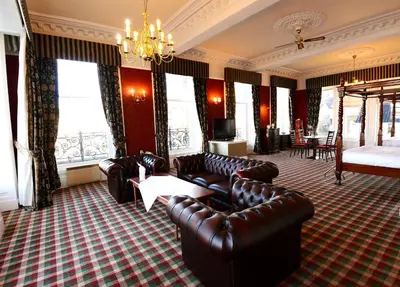 a living room with leather furniture and a chandelier at Columba Hotel in Oban