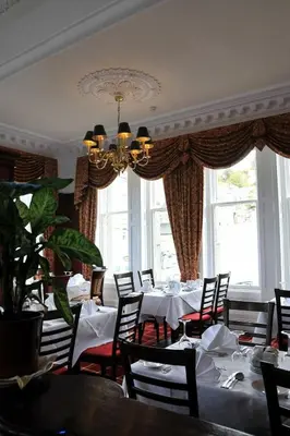 a dining room with tables and chairs and a chandelier at Columba Hotel in Oban