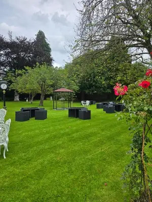 a park with benches and a gazebo in the grass at The Popinjay Hotel in Larkhall