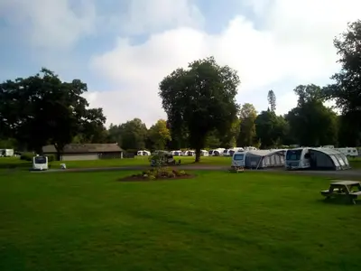 a park with tents and a picnic table in the grass at Callander Woods Holiday Park in Callander