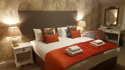 a bedroom with a large bed with orange and white pillows at Bridge of Orchy Hotel in Bridge of Orchy