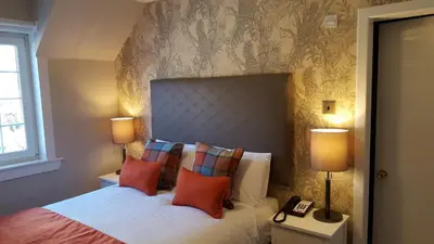 a bedroom with a bed with pillows and two lamps at Bridge of Orchy Hotel in Bridge of Orchy