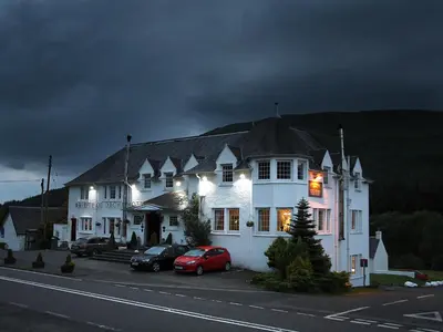 a large white house with cars parked in front of it at Bridge of Orchy Hotel in Bridge of Orchy