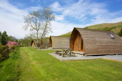 a wooden cabin with picnic tables in the grass at LOCH TAY HIGHLAND LODGES and GLAMPING PARK in Morenish