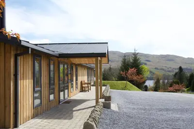 a building with a solar roof on a road at LOCH TAY HIGHLAND LODGES and GLAMPING PARK in Morenish