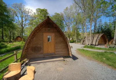 a small wooden building with a door in a yard at LOCH TAY HIGHLAND LODGES and GLAMPING PARK in Morenish