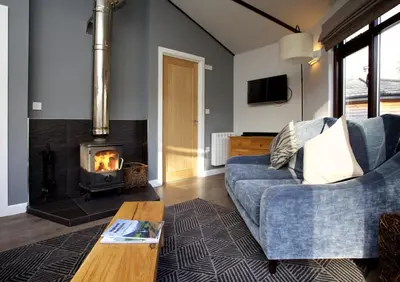 a living room with a blue couch and a fireplace at LOCH TAY HIGHLAND LODGES and GLAMPING PARK in Morenish