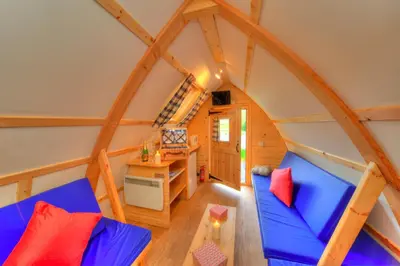 a room with a blue couch in a tiny house at LOCH TAY HIGHLAND LODGES and GLAMPING PARK in Morenish