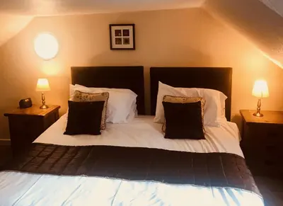 a bedroom with a bed with pillows and two lamps at Creebridge House Hotel in Newton Stewart