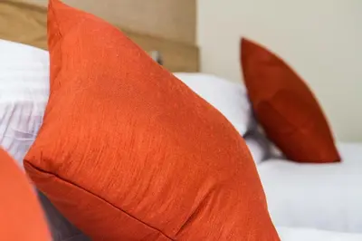 two orange pillows sitting on top of a bed at Hill Park Hotel in Rosyth