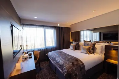 a hotel room with a large bed and a desk at The Redhurst Hotel Glasgow in Giffnock