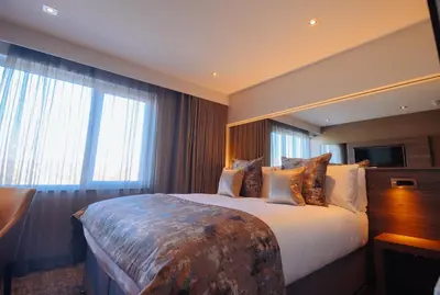 a hotel room with a large bed and windows at The Redhurst Hotel Glasgow in Giffnock